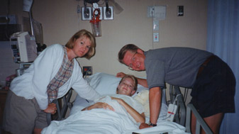 Child laying in a hospital bed with her parents above her