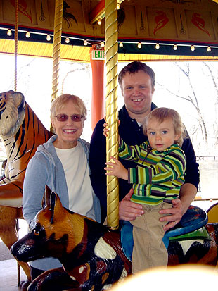 Marcia on a mary-go-round with son and grandson