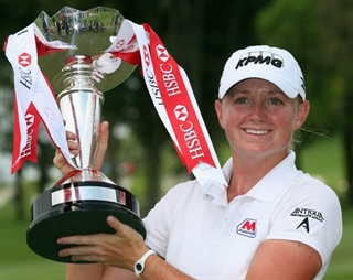 Female Golfer holding a trophy with ribbons on it.
